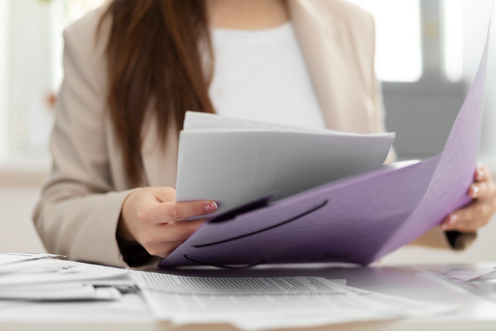 Frau prüft Unterlagen in einem Büro – rechtliche Unterstützung bei Arbeitsverträgen, Kündigungen und Gehaltsfragen.