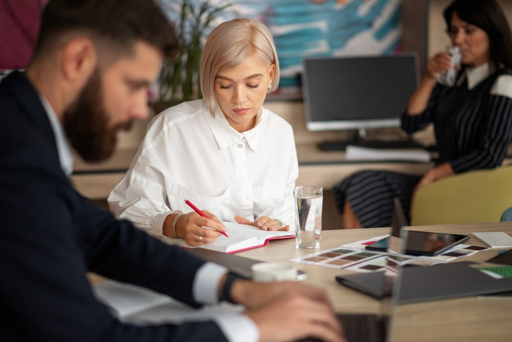 Mitarbeiter arbeiten konzentriert in modernem Büro, eine Frau macht Notizen – rechtliche Unterstützung für Unternehmen und Teams.